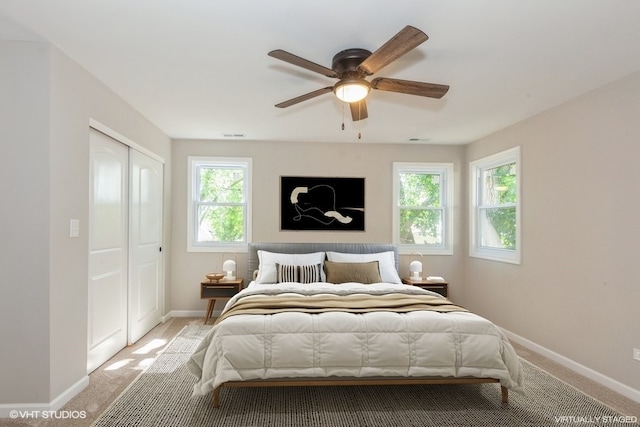 carpeted bedroom with a closet, multiple windows, and ceiling fan