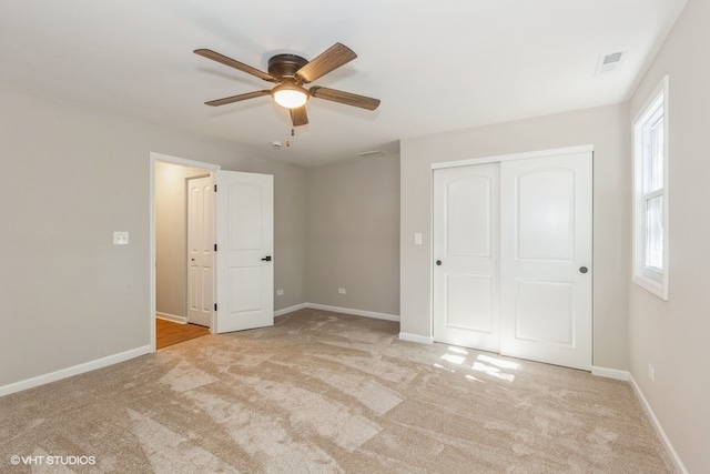 unfurnished bedroom featuring ceiling fan, a closet, light carpet, and multiple windows