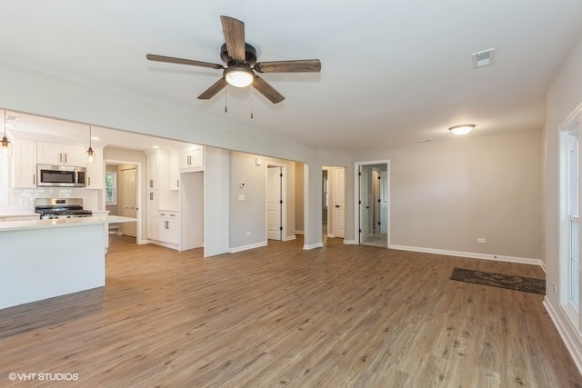 unfurnished living room featuring decorative columns, light hardwood / wood-style floors, and ceiling fan