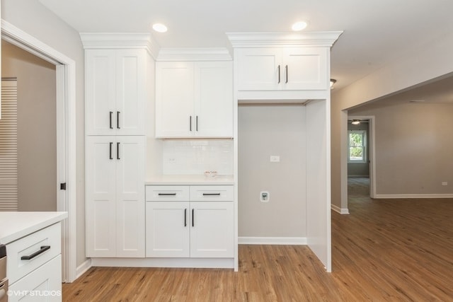 kitchen featuring light wood-type flooring, backsplash, and white cabinetry