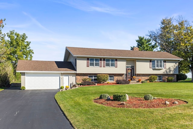 split foyer home featuring aphalt driveway, an attached garage, a front yard, and a chimney