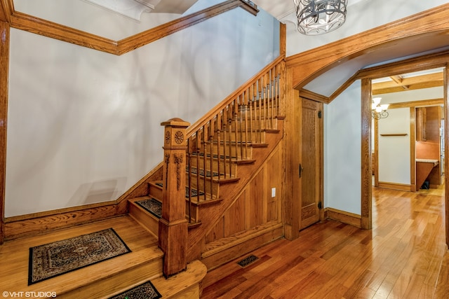 stairs featuring wood-type flooring and a chandelier