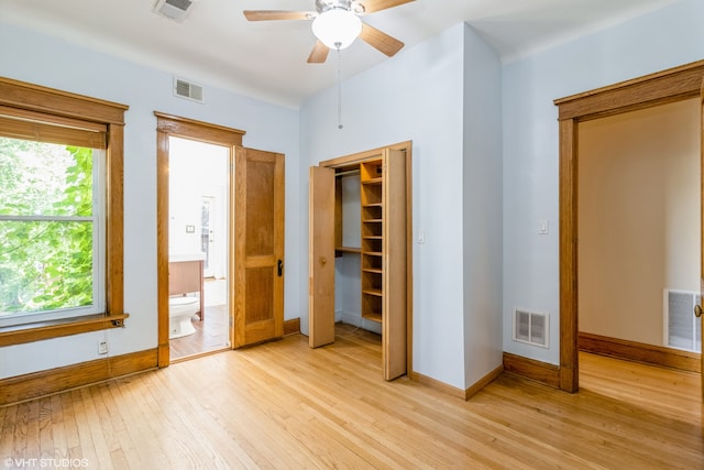 unfurnished bedroom featuring light wood-type flooring, a walk in closet, ceiling fan, and ensuite bathroom