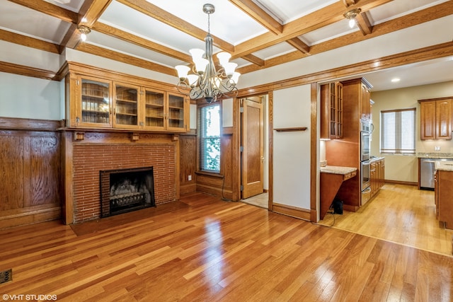 unfurnished living room with coffered ceiling, a brick fireplace, beam ceiling, an inviting chandelier, and light hardwood / wood-style flooring