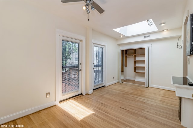 unfurnished room featuring light hardwood / wood-style flooring, a skylight, and ceiling fan