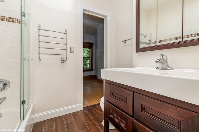 full bathroom featuring vanity, hardwood / wood-style flooring, toilet, and combined bath / shower with glass door