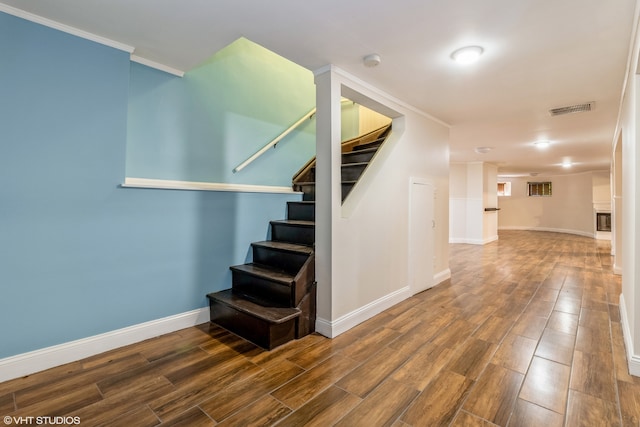 stairway featuring wood-type flooring and crown molding