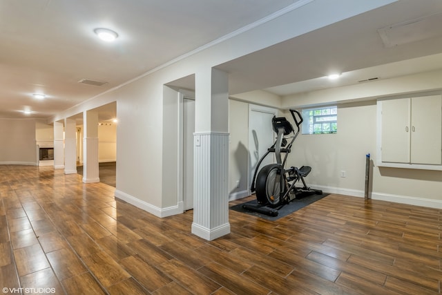 workout area with dark hardwood / wood-style floors and crown molding