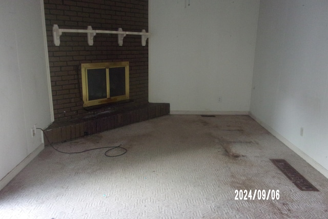 unfurnished living room featuring carpet floors and a brick fireplace