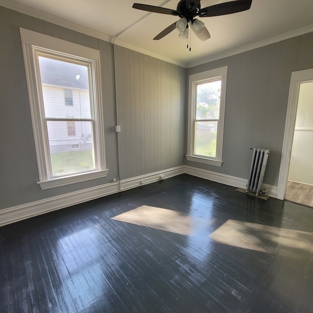 unfurnished room featuring ceiling fan, ornamental molding, dark wood-type flooring, and radiator heating unit