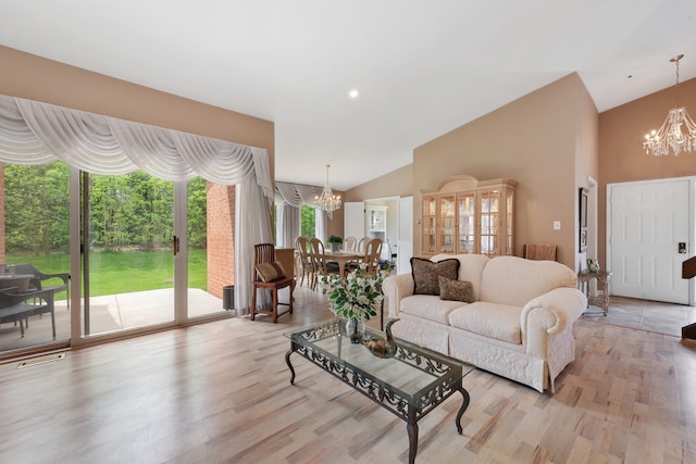 living room with a notable chandelier, high vaulted ceiling, and light hardwood / wood-style flooring