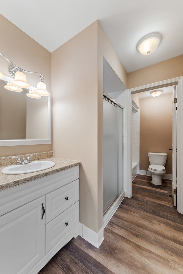 bathroom featuring wood-type flooring, vanity, toilet, and an enclosed shower