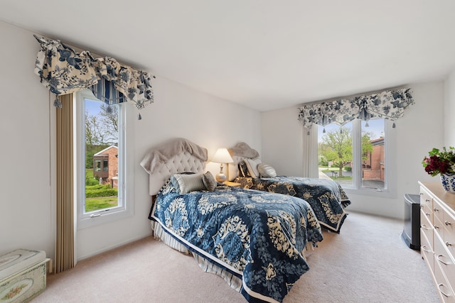 bedroom featuring light colored carpet and multiple windows