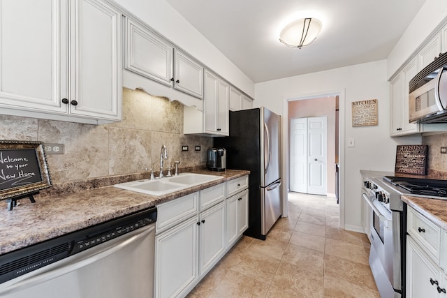 kitchen with appliances with stainless steel finishes, white cabinetry, backsplash, light tile patterned floors, and sink