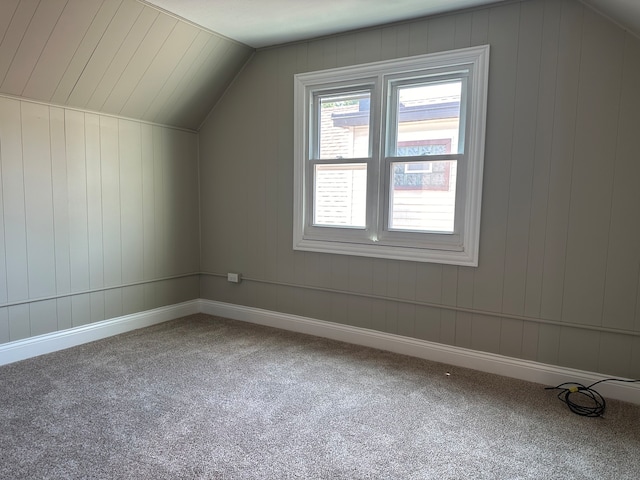 bonus room featuring lofted ceiling, wood walls, and carpet floors