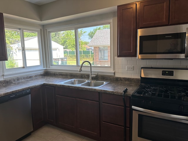 kitchen featuring appliances with stainless steel finishes, light tile patterned flooring, tasteful backsplash, dark brown cabinetry, and sink