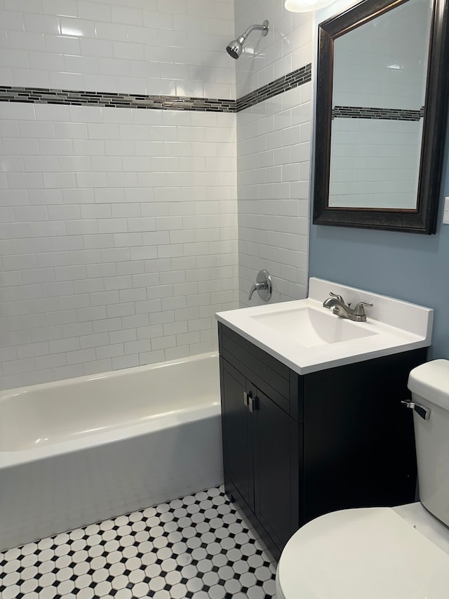 full bathroom featuring tiled shower / bath combo, vanity, and toilet