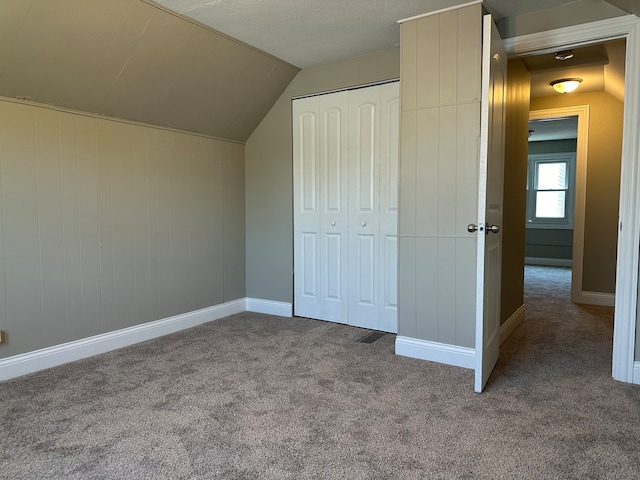 unfurnished bedroom featuring lofted ceiling, a closet, and carpet floors