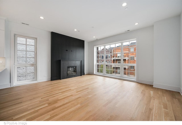 unfurnished living room with light wood-type flooring and a large fireplace