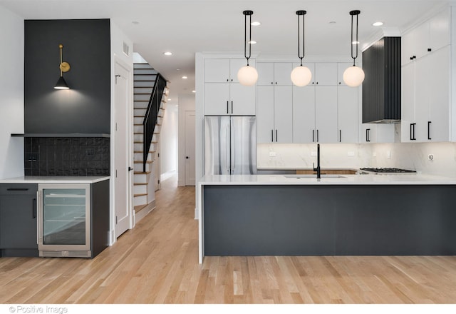 kitchen with wine cooler, sink, decorative light fixtures, white cabinetry, and appliances with stainless steel finishes