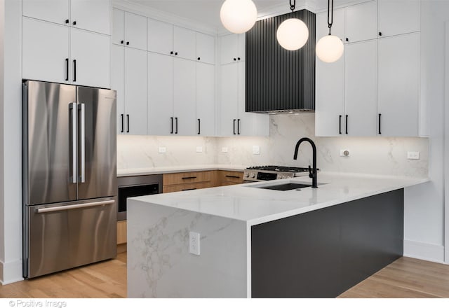 kitchen featuring appliances with stainless steel finishes, light hardwood / wood-style floors, white cabinetry, pendant lighting, and sink