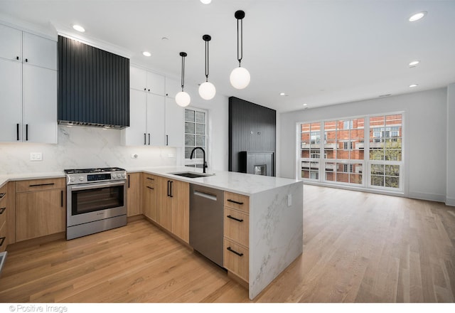 kitchen featuring pendant lighting, white cabinets, light hardwood / wood-style flooring, stainless steel appliances, and light stone countertops