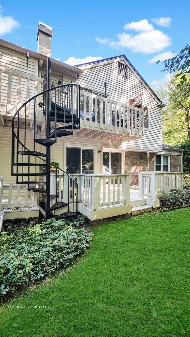 rear view of property featuring a wooden deck and a lawn