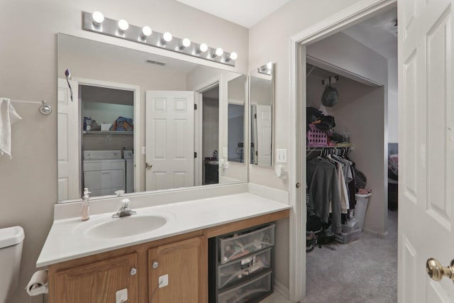 bathroom featuring toilet, vanity, a walk in closet, and independent washer and dryer