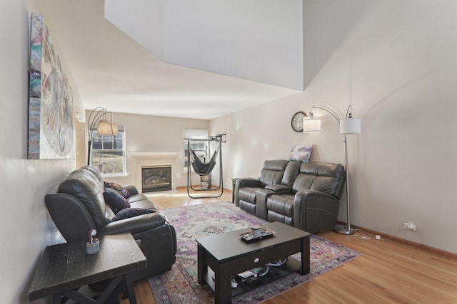 living room with a glass covered fireplace, baseboards, and wood finished floors