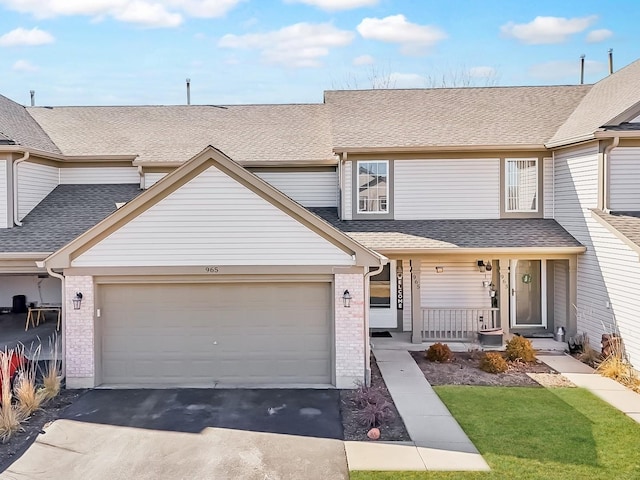 multi unit property featuring a garage, brick siding, a porch, and roof with shingles