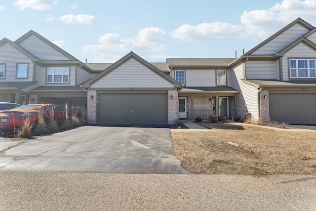 view of front of house with brick siding, an attached garage, and aphalt driveway