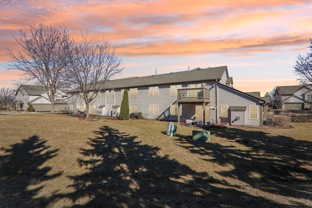 back of property at dusk featuring a lawn