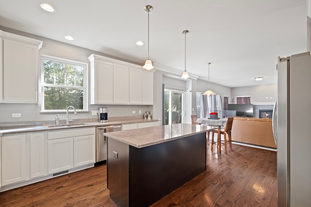 kitchen featuring a center island, sink, white cabinetry, stainless steel appliances, and dark hardwood / wood-style flooring