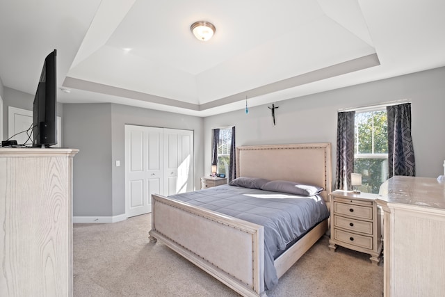 carpeted bedroom featuring a closet and a raised ceiling