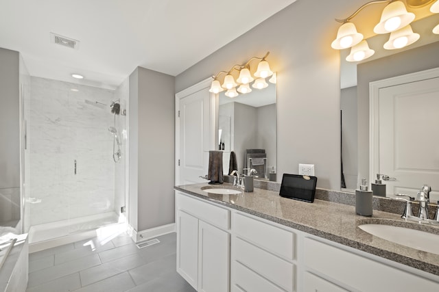 bathroom with a shower with door, vanity, and tile patterned floors