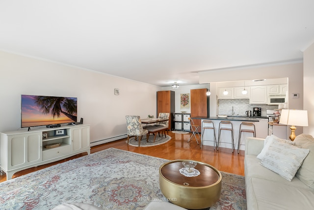 living room with ornamental molding, hardwood / wood-style floors, a baseboard heating unit, and sink