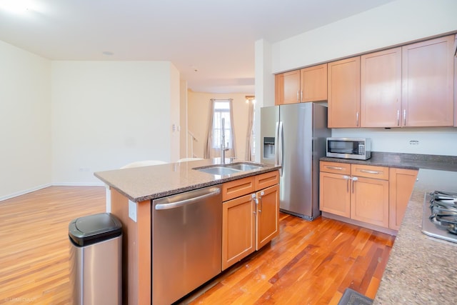 kitchen featuring a kitchen island with sink, light wood-type flooring, stainless steel appliances, and light brown cabinetry