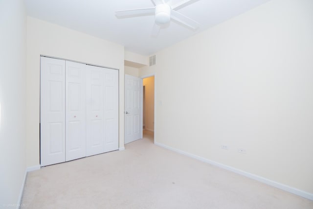 unfurnished bedroom with ceiling fan, a closet, and light colored carpet