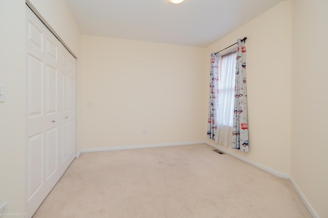 unfurnished bedroom featuring light colored carpet and a closet