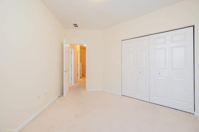 unfurnished bedroom with light carpet and a closet