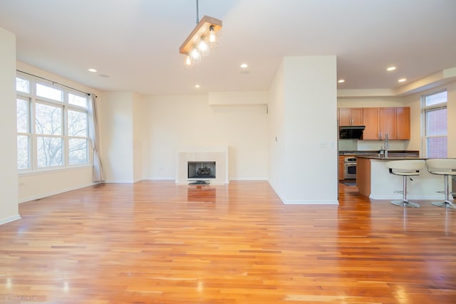 unfurnished living room with light wood-type flooring and sink