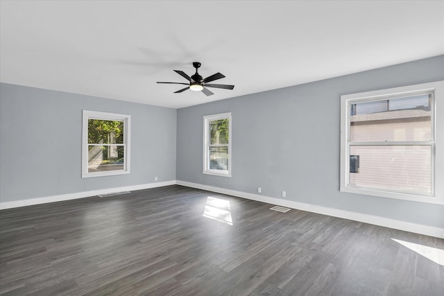 empty room featuring ceiling fan, dark hardwood / wood-style floors, and a healthy amount of sunlight