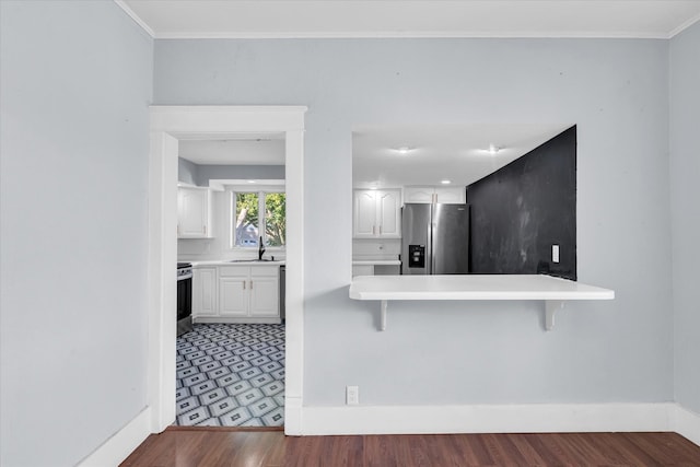 kitchen featuring white cabinets, kitchen peninsula, a kitchen bar, stainless steel appliances, and dark hardwood / wood-style flooring