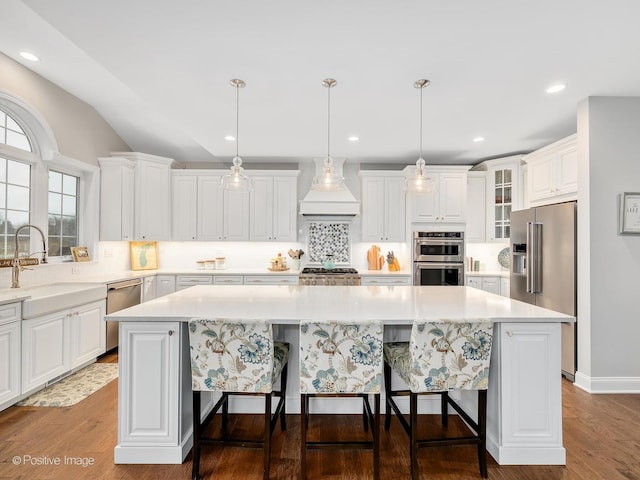 kitchen featuring white cabinetry, decorative light fixtures, a kitchen island, and appliances with stainless steel finishes