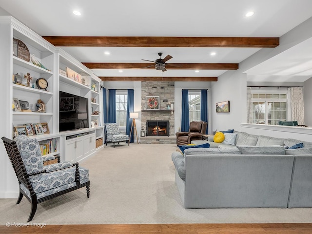 living room with beamed ceiling, ceiling fan, light carpet, and a fireplace