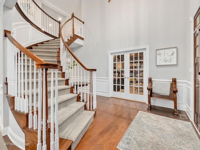 entrance foyer featuring a towering ceiling, wood-type flooring, and french doors