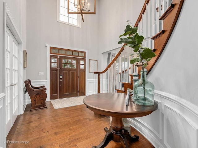 entryway with an inviting chandelier, wood-type flooring, and a high ceiling