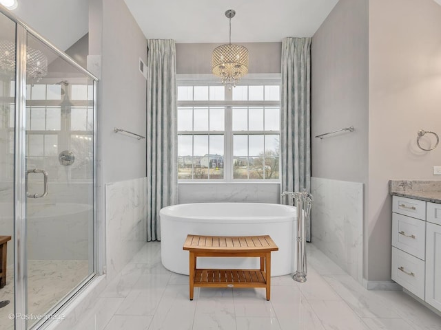 bathroom featuring vanity, plus walk in shower, a chandelier, and tile walls