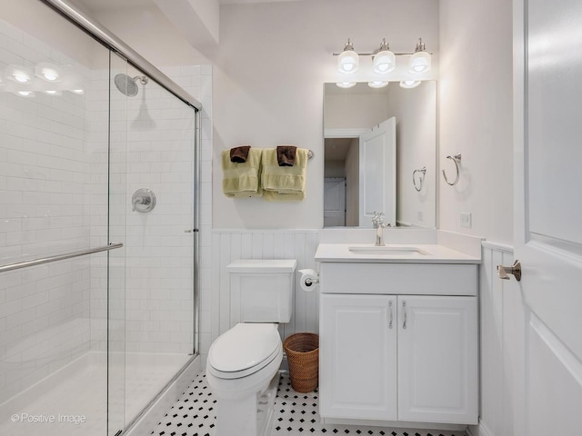 bathroom with tile patterned floors, vanity, toilet, and a shower with door