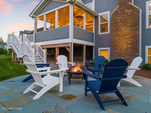 patio terrace at dusk with an outdoor fire pit and a sunroom